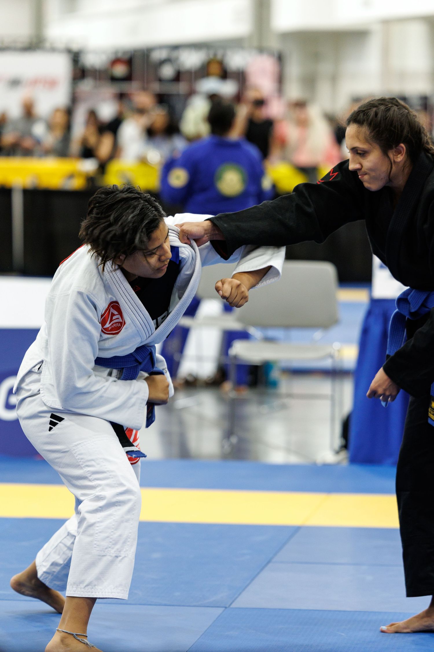 Martial artist in white gi executing a dynamic throwing technique during competition.