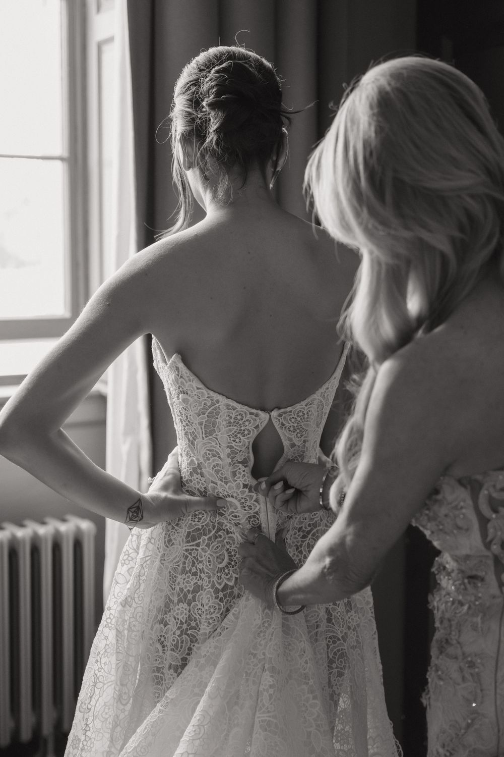 A sequence showing the back details of white lace wedding dresses being adjusted.