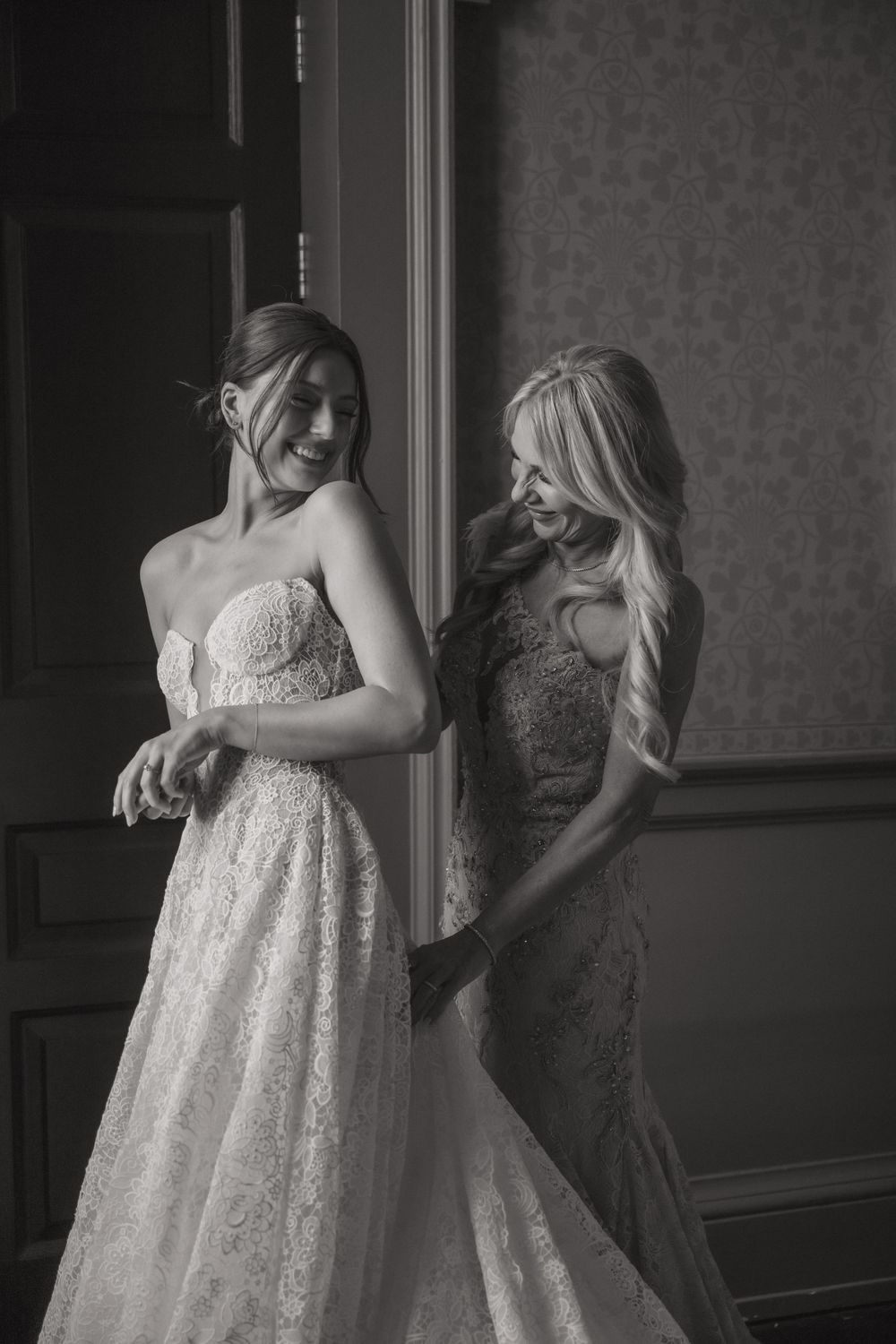 Final wedding dress adjustments being made in an elegant room.