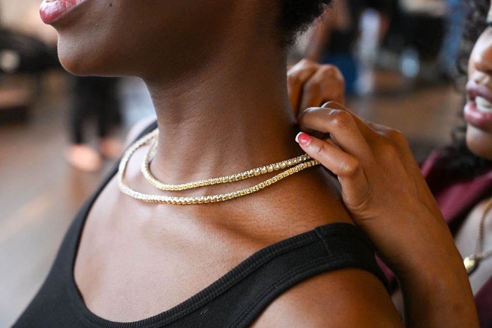 Close up view of gold jewelry and necklaces worn with a black top.