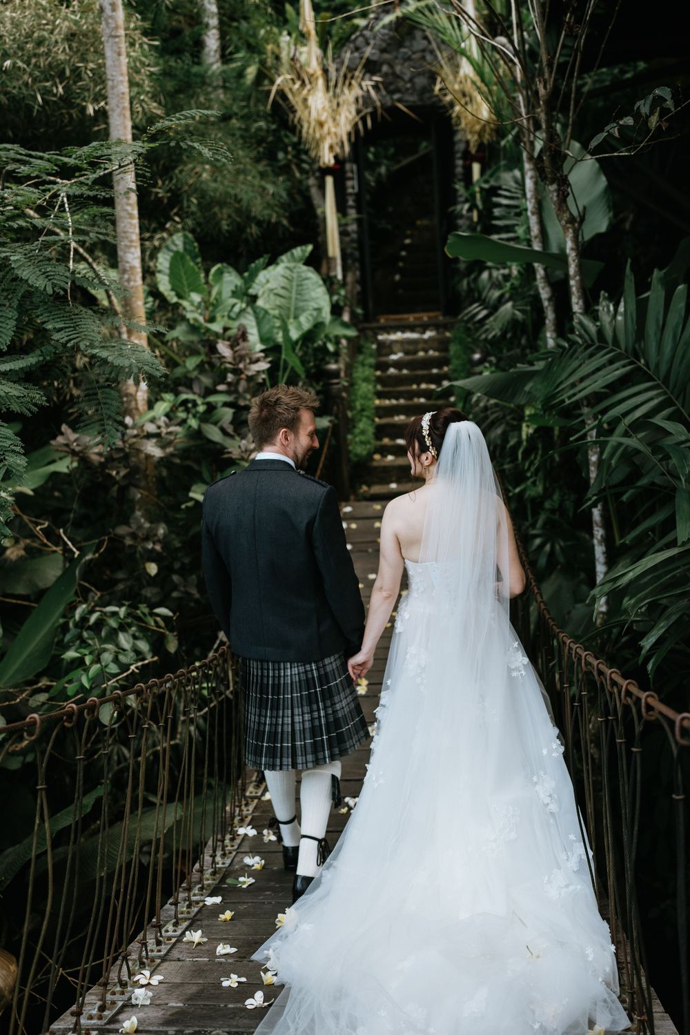 A romantic garden walkway with white flower petals scattered along the wooden path.