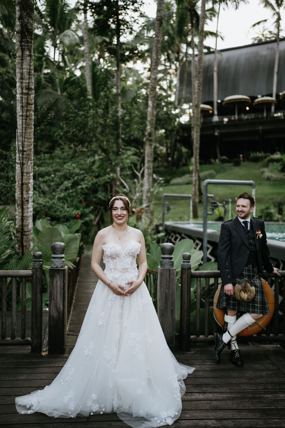 Wedding portraits on a wooden deck surrounded by tropical landscaping and palm trees.