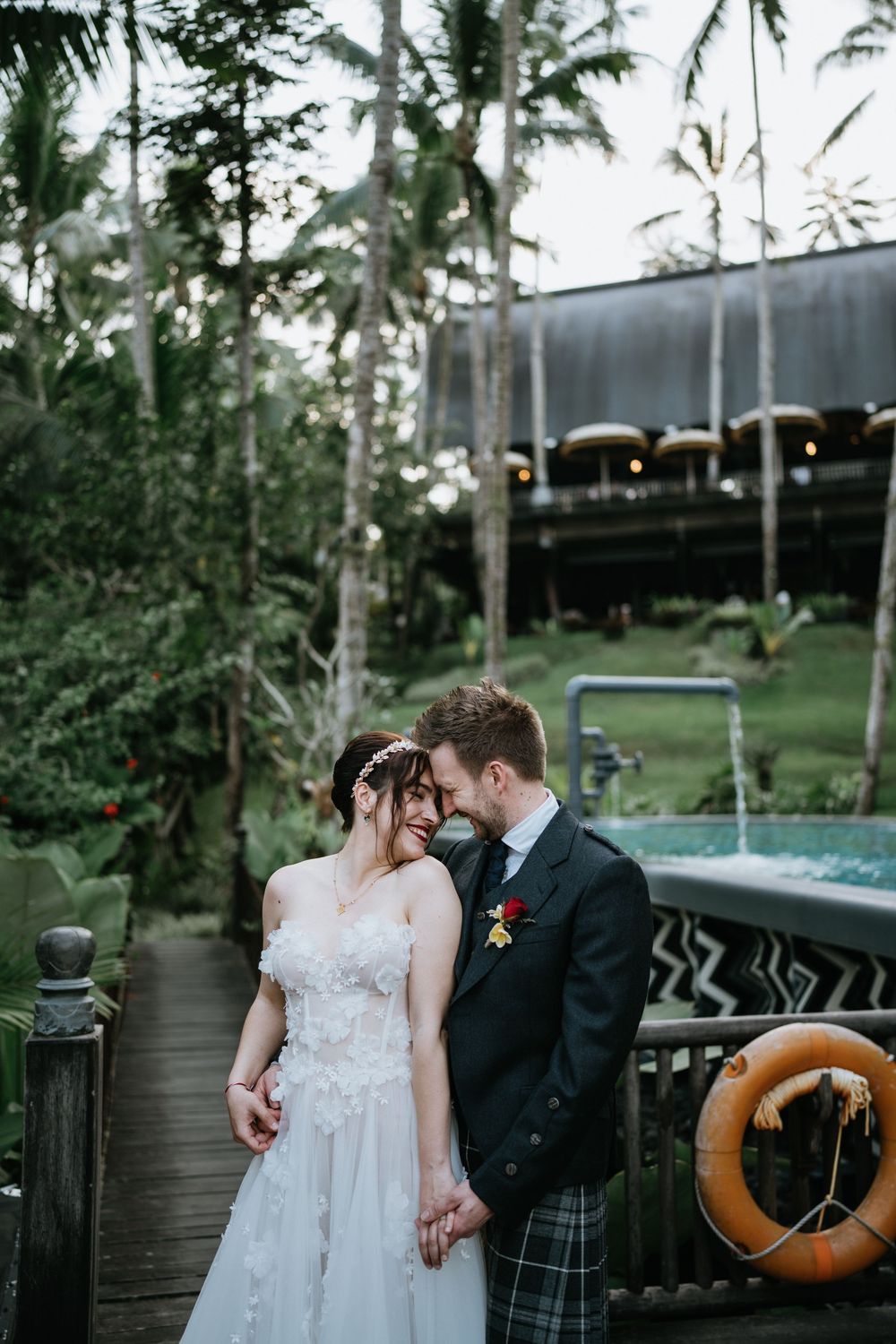 Intimate wedding moments captured on a wooden boardwalk with tropical scenery.
