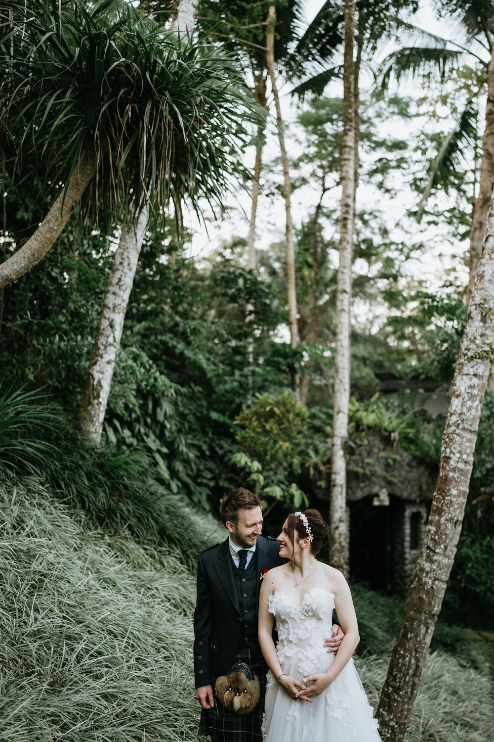A romantic wedding photoshoot among tall palm trees and lush tropical greenery.