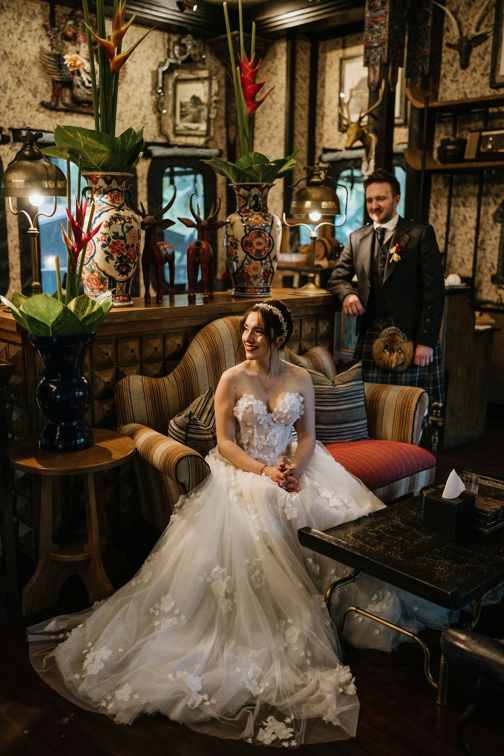 A stunning white wedding gown with intricate lace details fills the frame in a rustic indoor setting.