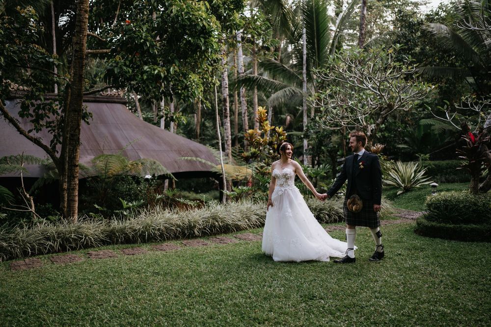 A beautiful wedding scene unfolds in a lush garden setting with palm trees and greenery.