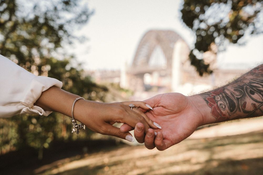 Close-up view of hands gently touching and connecting in soft sunlight outdoors.