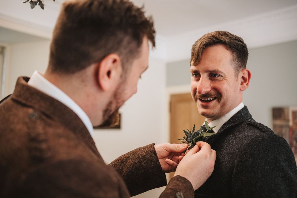Two men in suits sharing a laugh during a candid moment at what appears to be a formal event.