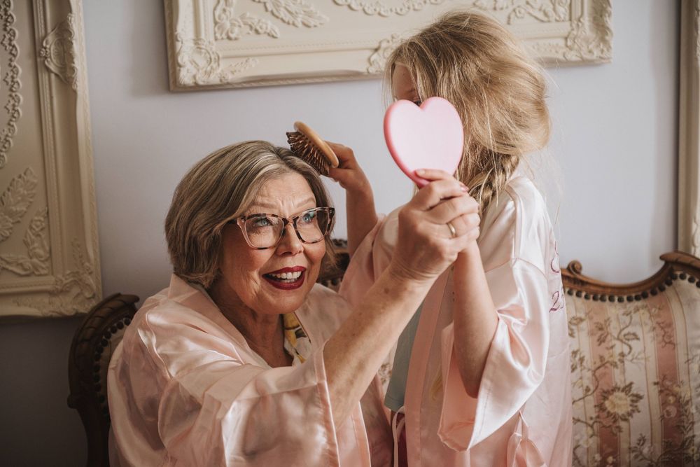 A joyful moment shared between a woman in glasses and a child holding a heart-shaped mirror in a vintage-style room.