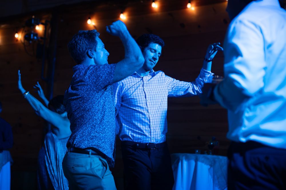 People dancing in a dark room illuminated by warm overhead lights creating a blue-tinted nightclub atmosphere.