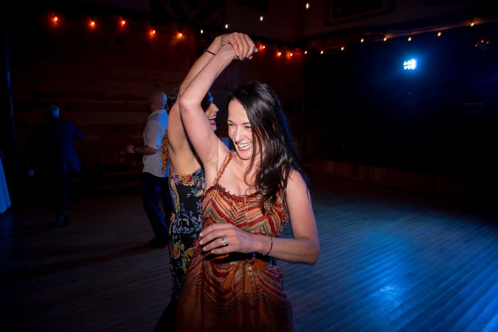 Couples dance together on a dimly lit dance floor with red and blue lighting creating a romantic atmosphere.