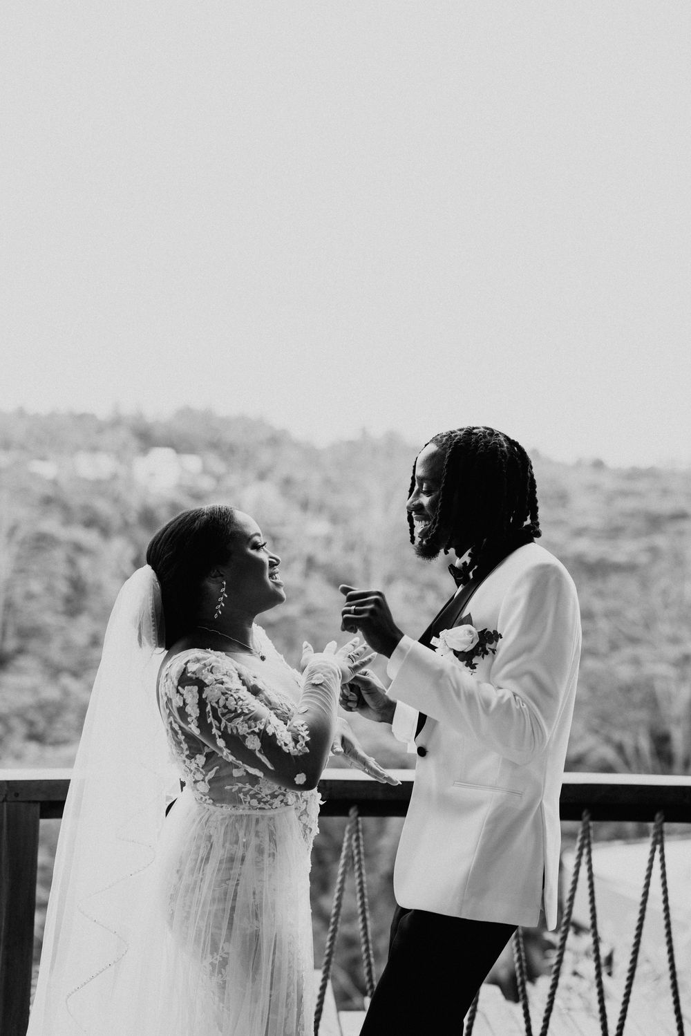 A joyful black and white wedding photo capturing a candid dancing moment on an outdoor terrace.