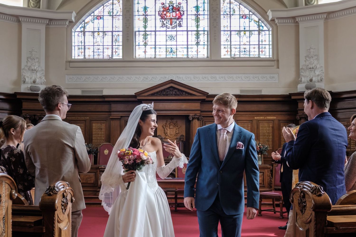 A wedding ceremony takes place in a beautiful church with stained glass windows and wooden pews.