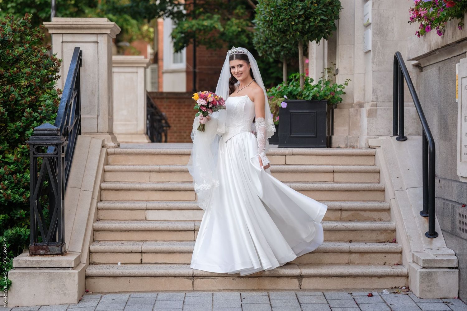 A series of sequential photos showing a bridal procession down elegant stone steps decorated with floral arrangements.