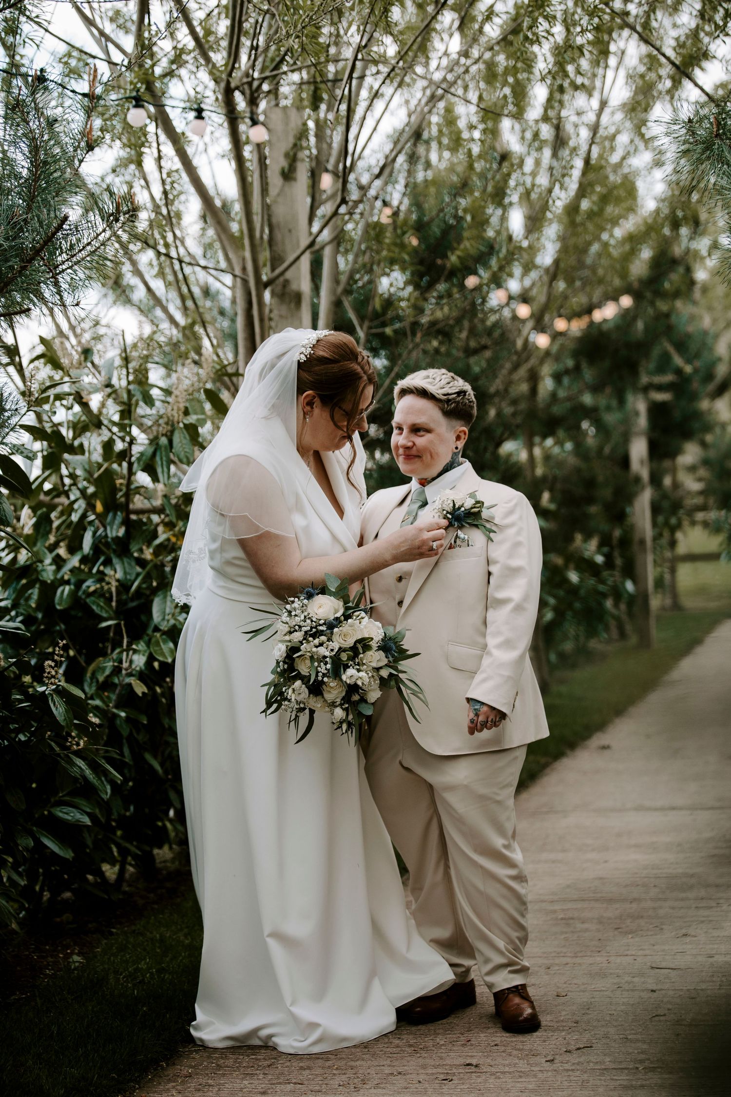 A romantic wedding moment captured on a tree-lined garden pathway at Coton Farm Wedding Venue, Lichfield, Staffordshire