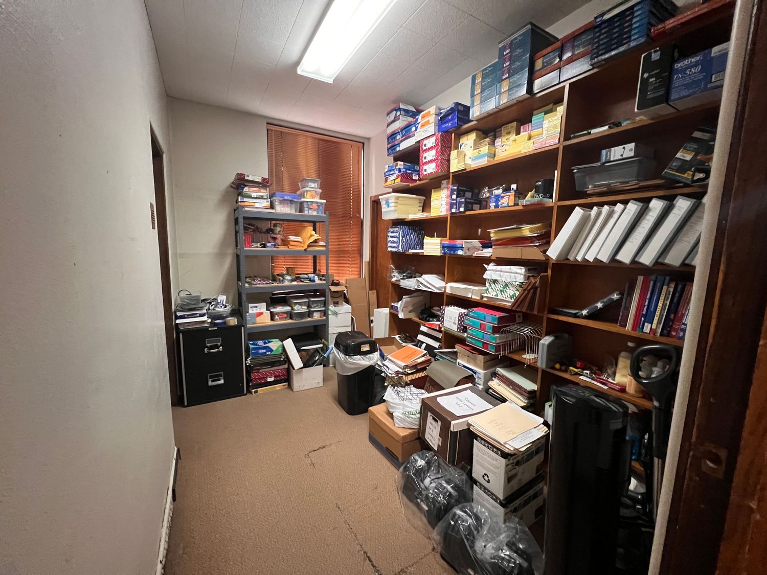 Storage room filled with shelves containing boxes, books, and various supplies.