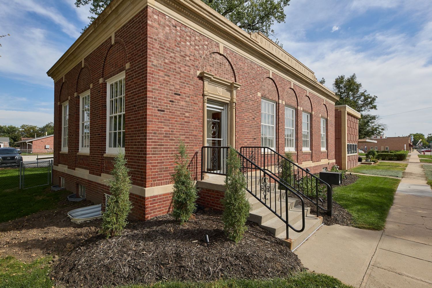Traditional red brick church building exterior with arched windows and landscaped grounds.