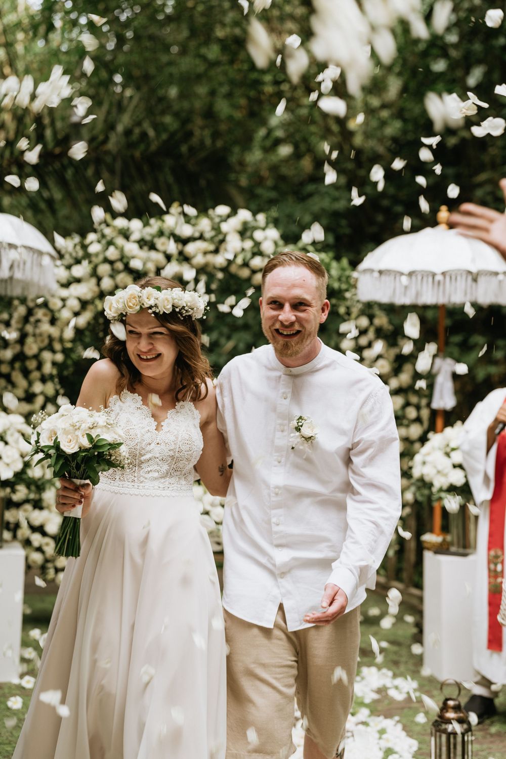 Wedding celebration with flower petals falling as couple enjoys their special moment in white attire.