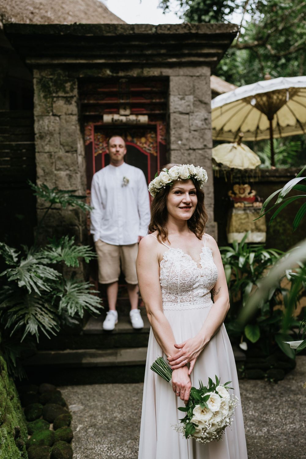 Wedding portraits in a garden setting with stone walls and decorative parasols.