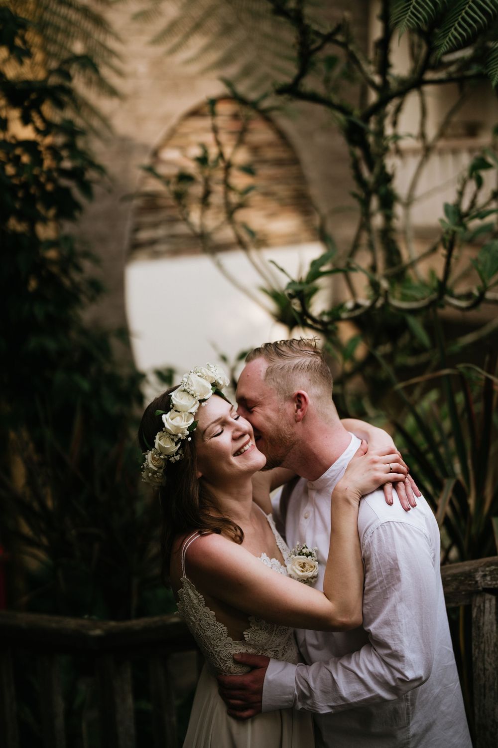 Intimate wedding portraits captured in natural garden setting with floral details.