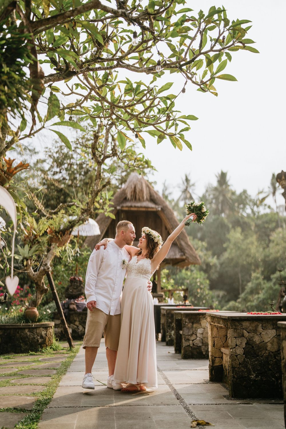 Couple sharing intimate moments on a stone pathway surrounded by tropical greenery.