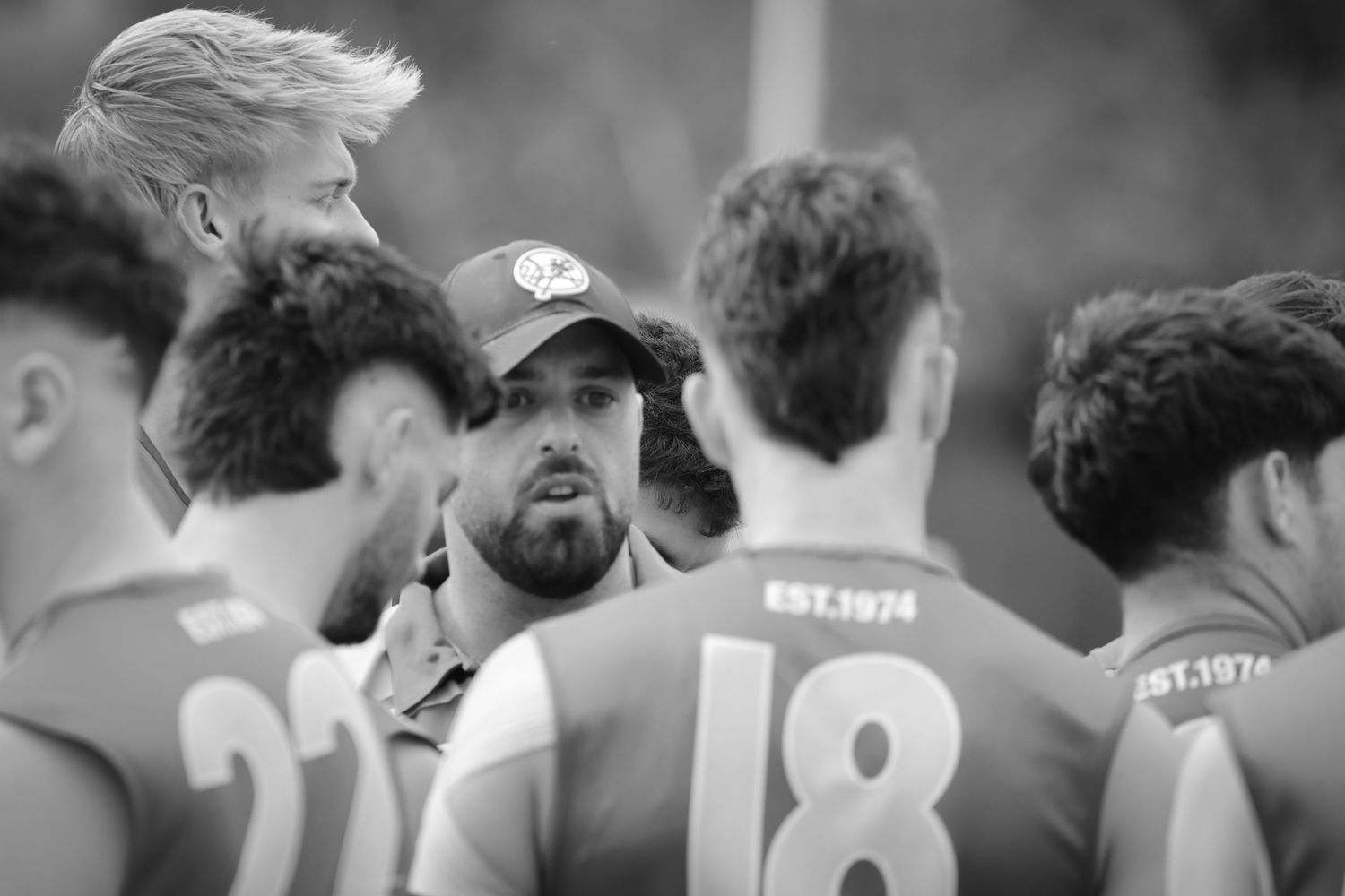 Sports team huddles together during a black and white athletic game moment.
