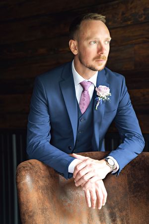 A sequence of wedding photography shots showing a groom in a navy suit with pink tie and boutonniere posing thoughtfully.