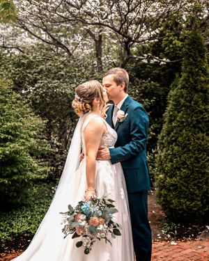 A romantic wedding scene with blooming white flowers and greenery surrounds a couple in a garden setting.