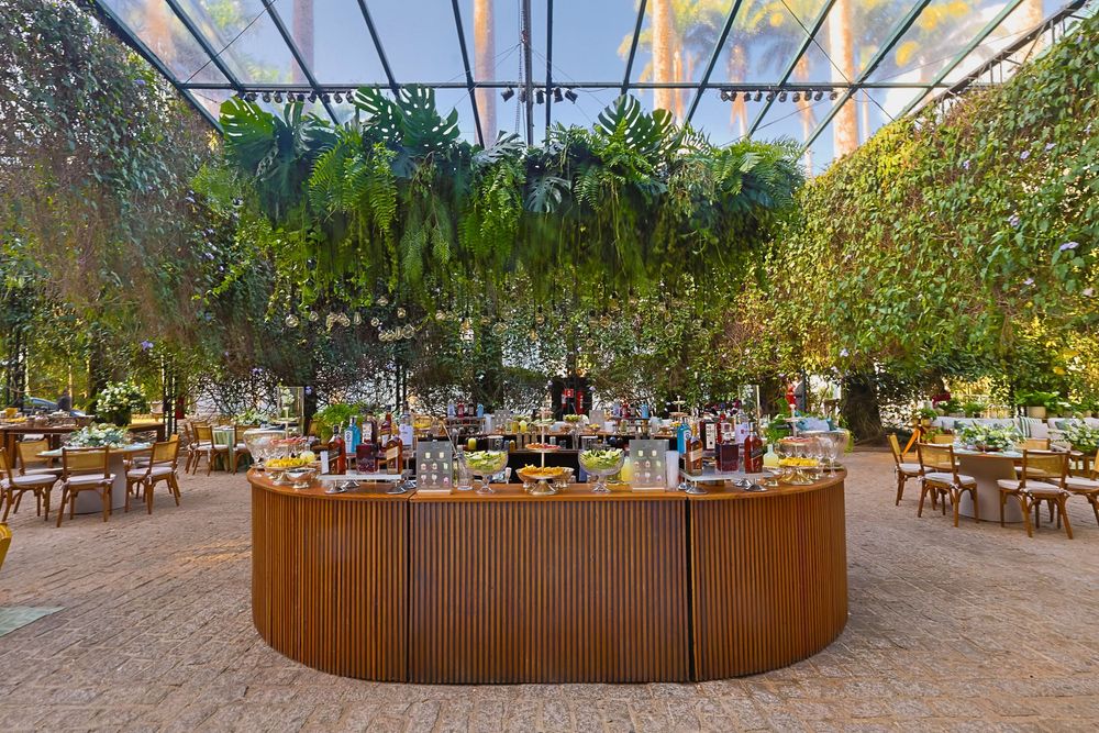 Panoramic view of an outdoor wedding venue with string lights hanging overhead and wooden seating arrangements.