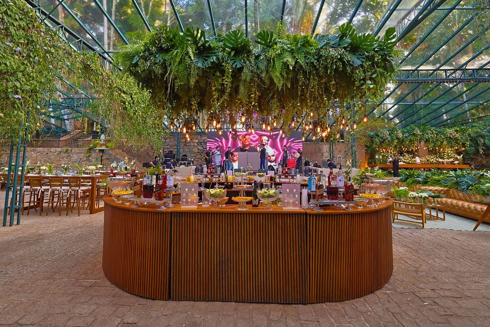 A greenhouse venue with natural light features hanging floral installations and wooden dining tables arranged for an event.