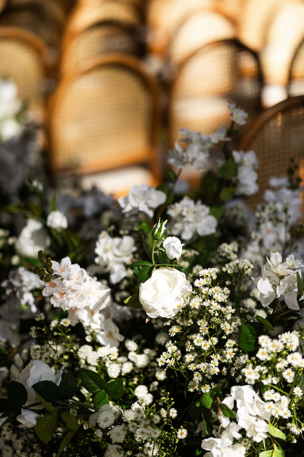 White floral arrangement with delicate blooms and greenery displayed against a soft bokeh background.