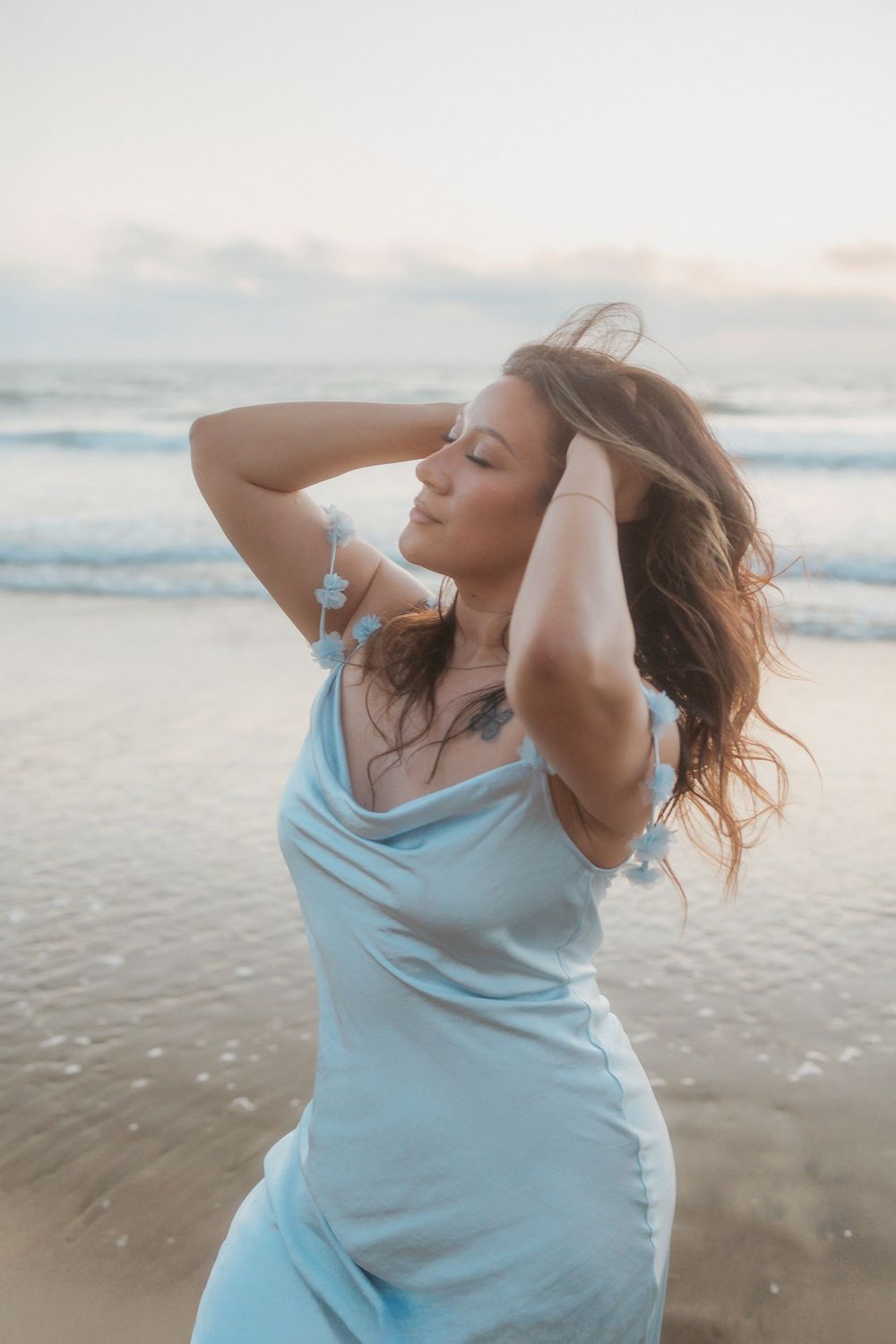 A light blue sundress catches the coastal breeze during a serene beach photoshoot at golden hour.