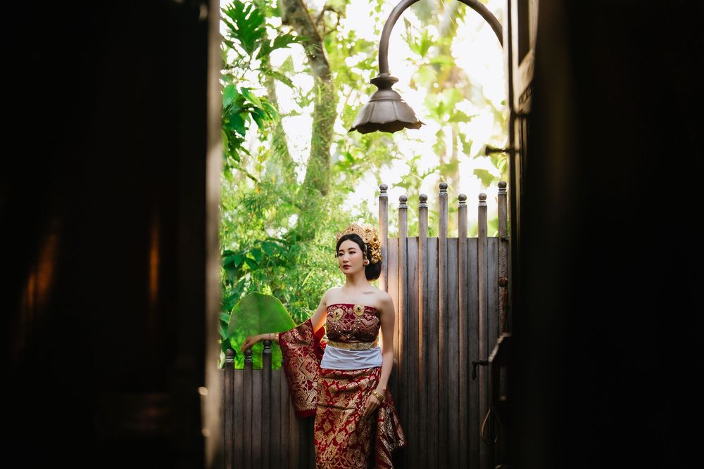 Silhouetted figure in traditional dress against garden backdrop.