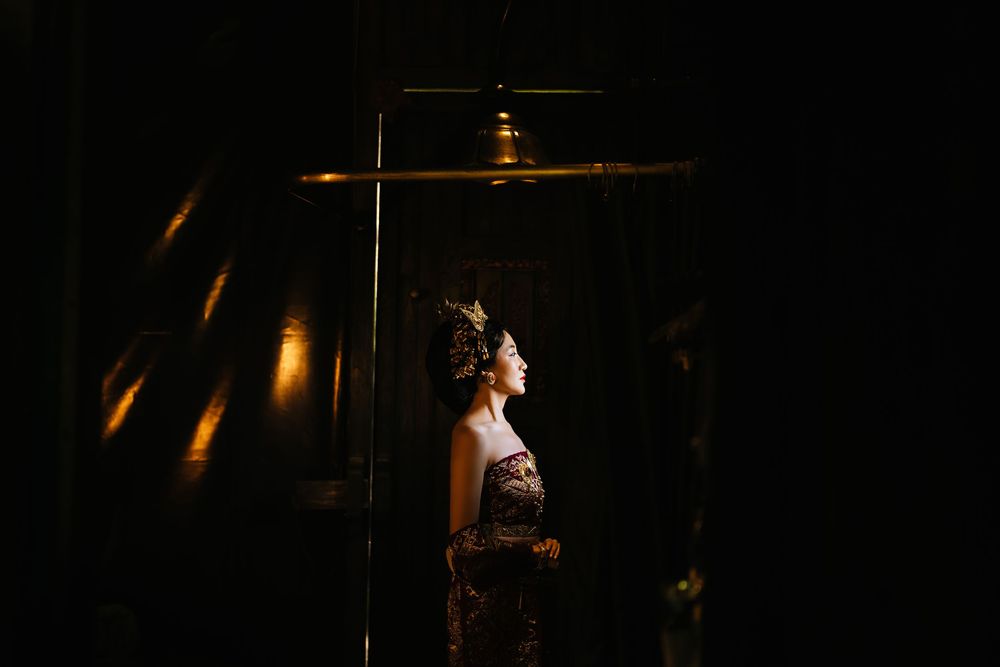 Artistic low-light portrait with golden highlights against a dark background.