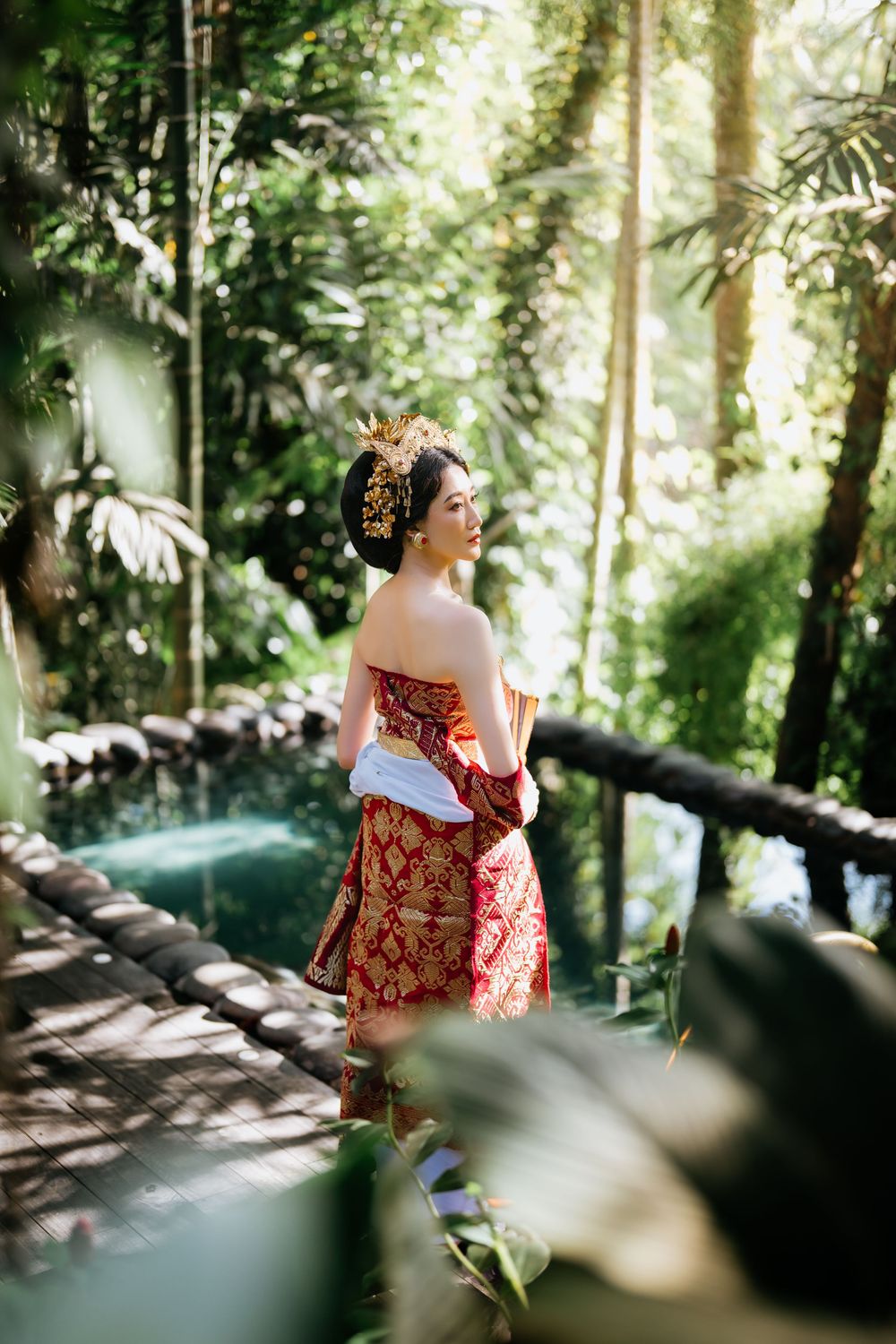 Outdoor portrait session featuring traditional burgundy dress and golden accessories in natural light.