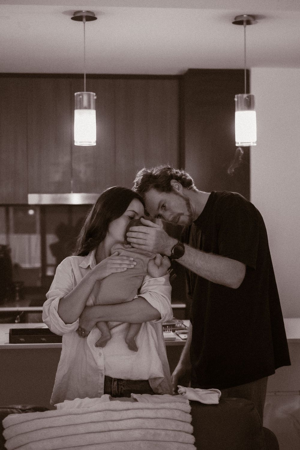 An intimate family moment captured in black and white under pendant lights.