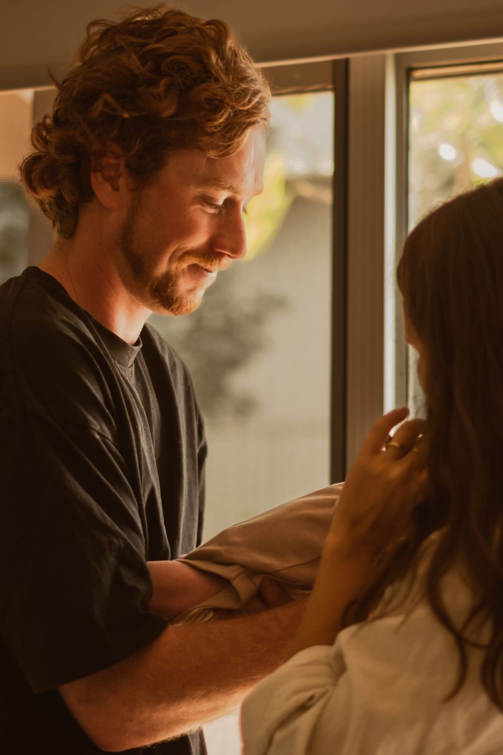 An intimate moment between parents sharing a loving gaze while holding their baby.