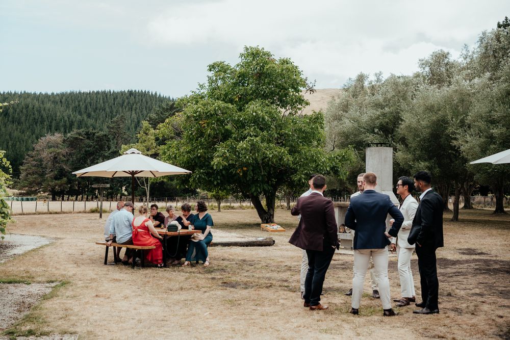 Wedding guests outside on a golden lawn at Tironui Farm Martinborough by August and Vine