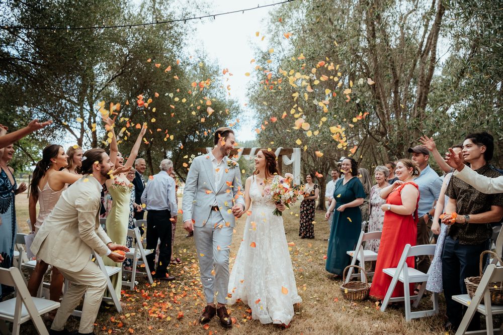 Colourful petal confetti falls on wedding couple as they walk down aisle at Tironui Farm Martinborough by August and Vine