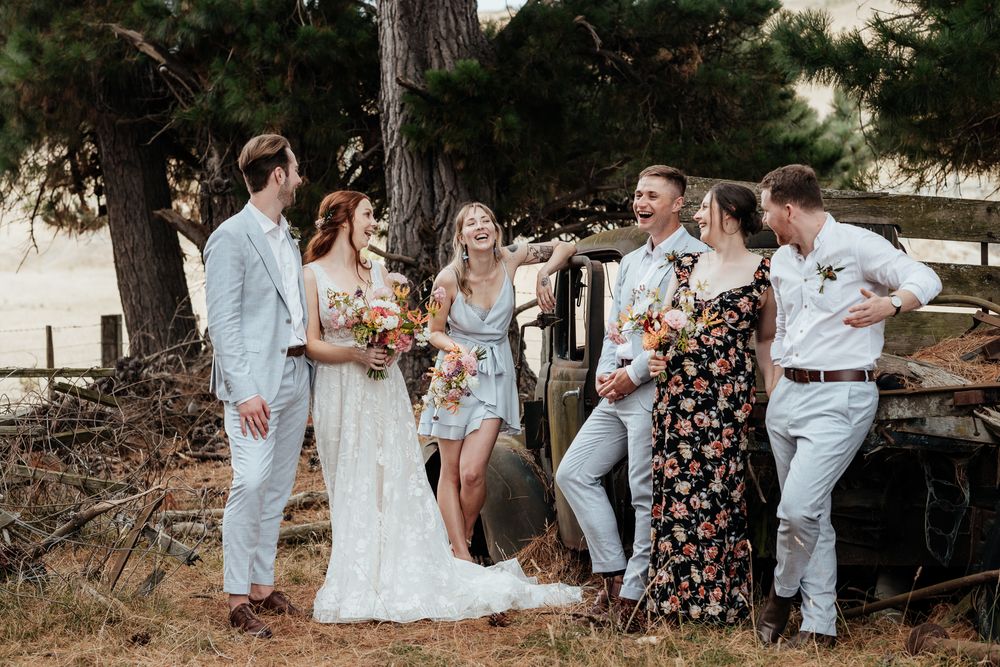 Laughing bridal party stand by an old farm truck at Tironui Farm Martinborough by August and Vine
