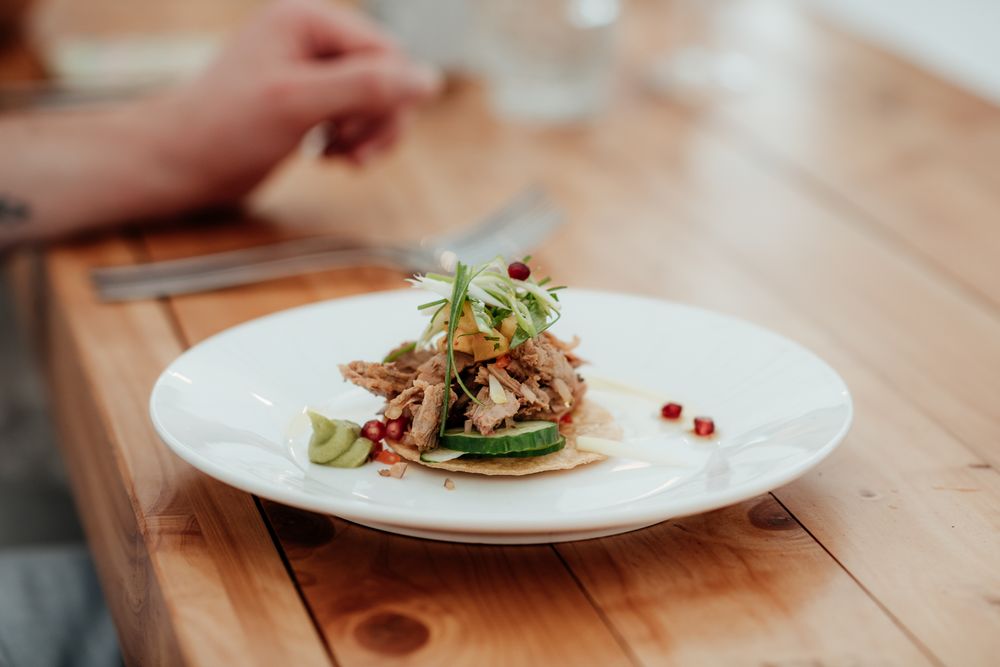 A gourmet taco with fresh microgreens and garnishes served on a white plate at Tironui Farm Martinborough by August and Vine