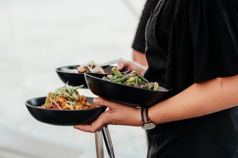 A server carries plates of fresh salads and side dishes at Tironui Farm Martinborough by August and Vine