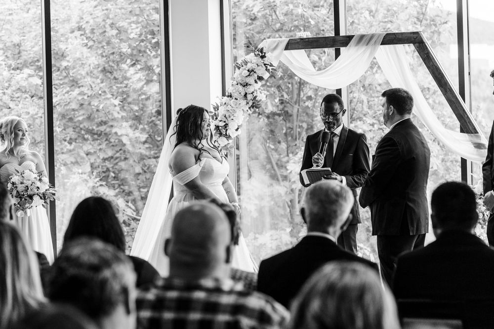 Wedding ceremony guests seated in rows watch attentively during an indoor celebration.