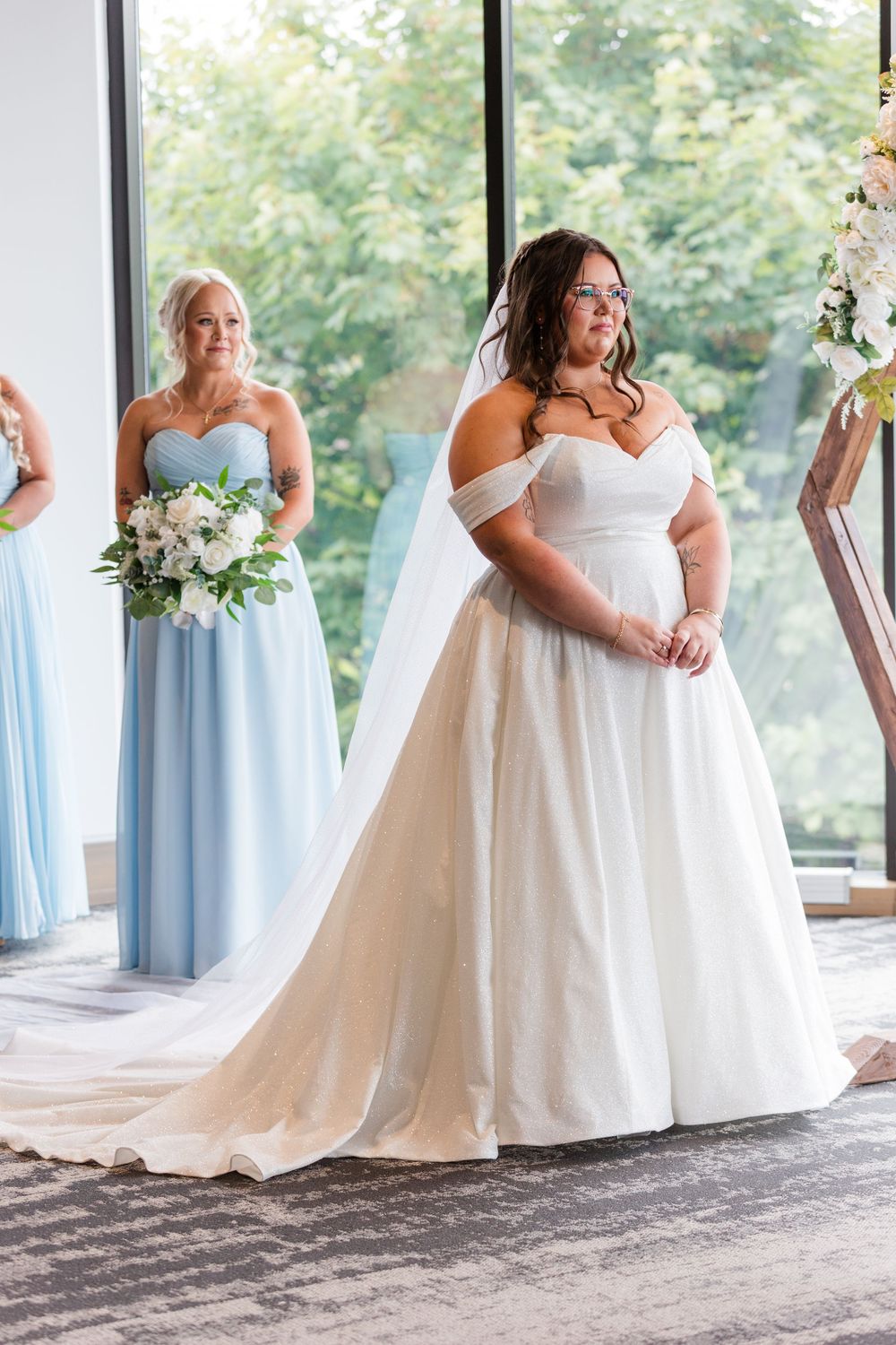 Bridesmaids in light blue dresses stand alongside a bride in white during a wedding ceremony.