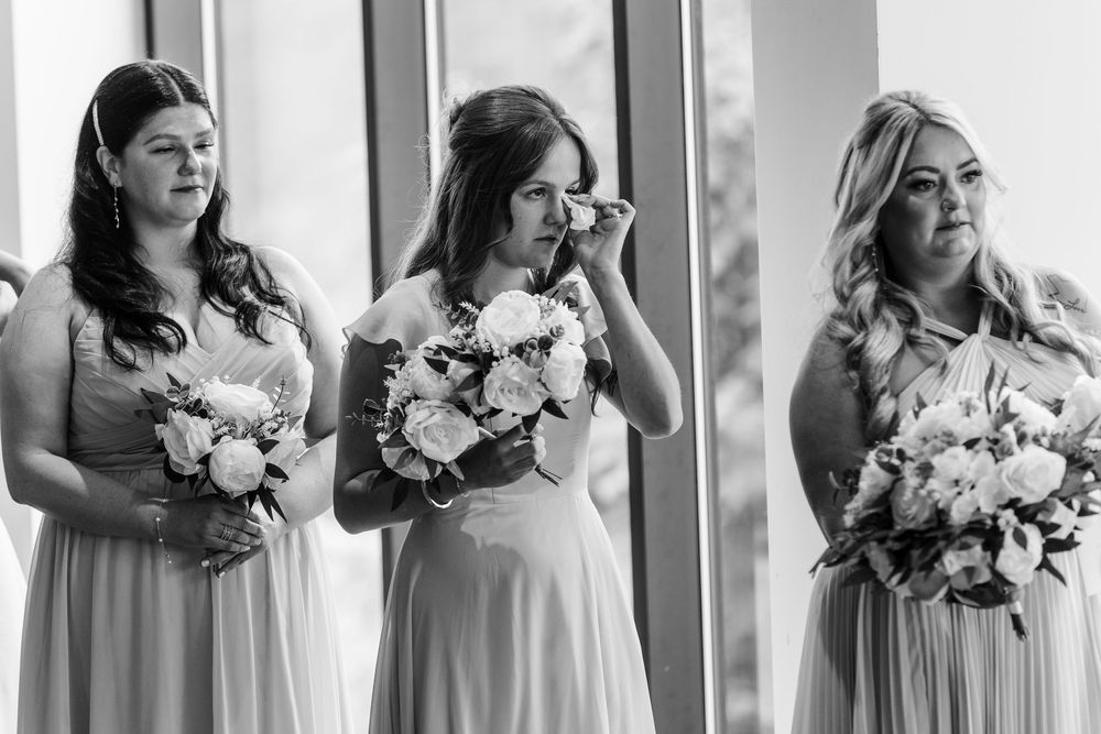 Row of bridesmaids in light blue dresses holding white floral bouquets.