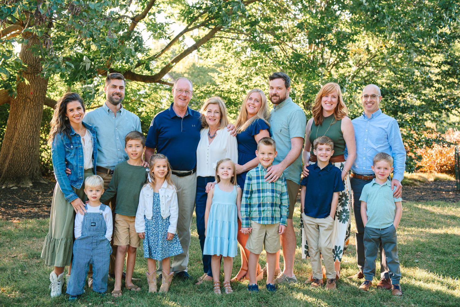 Large multi-generational family group photo outdoors with coordinated blue and neutral clothing.