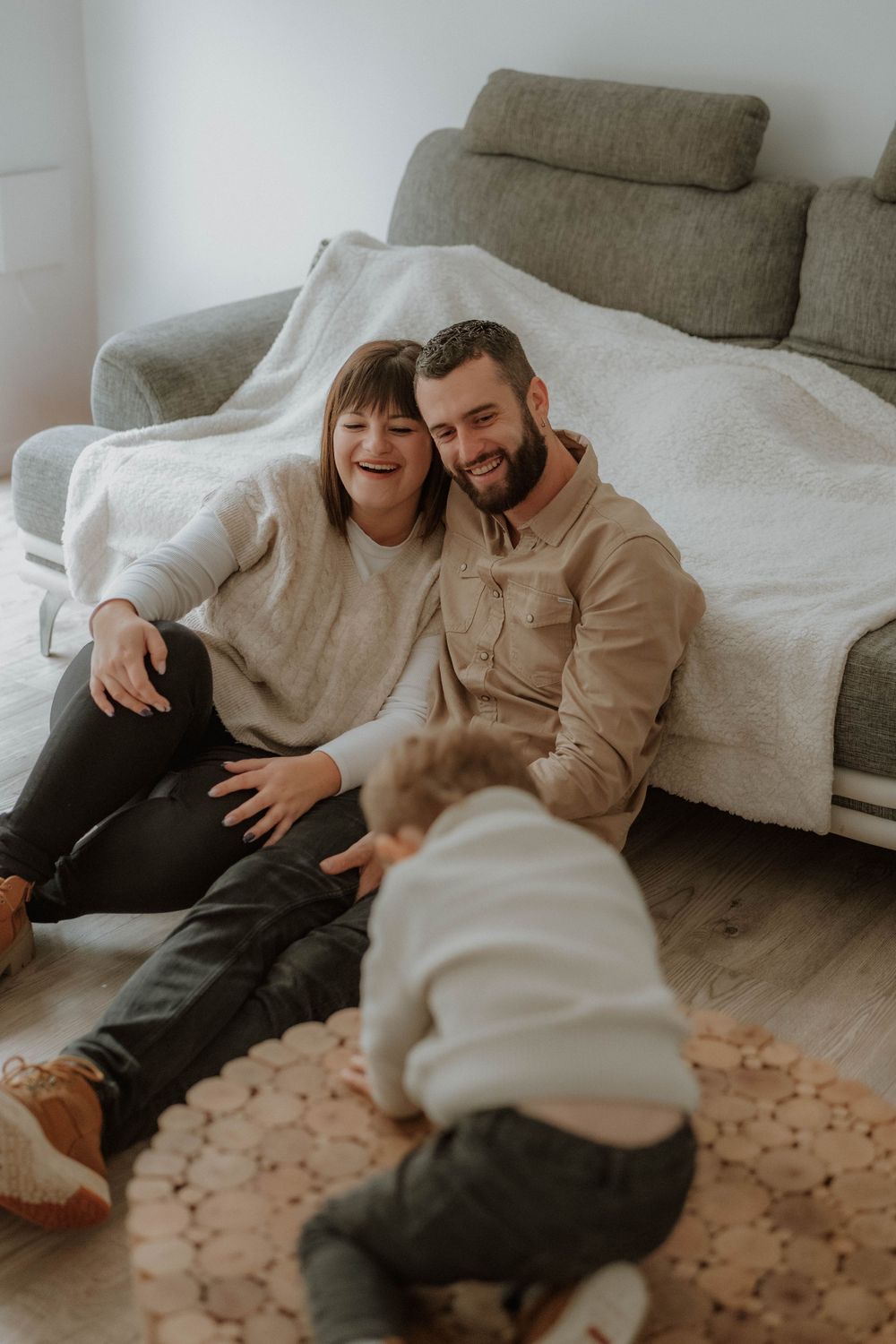 A couple relaxes together on a cozy couch with a textured rug below, sharing intimate moments in warm lighting.