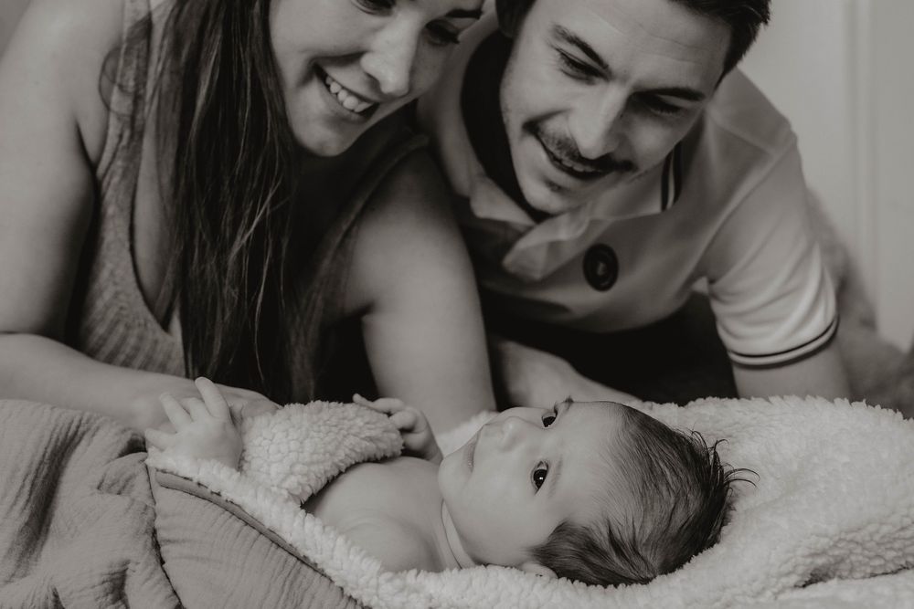 Black and white photo collage showing tender family moments with a newborn baby and parents at home.