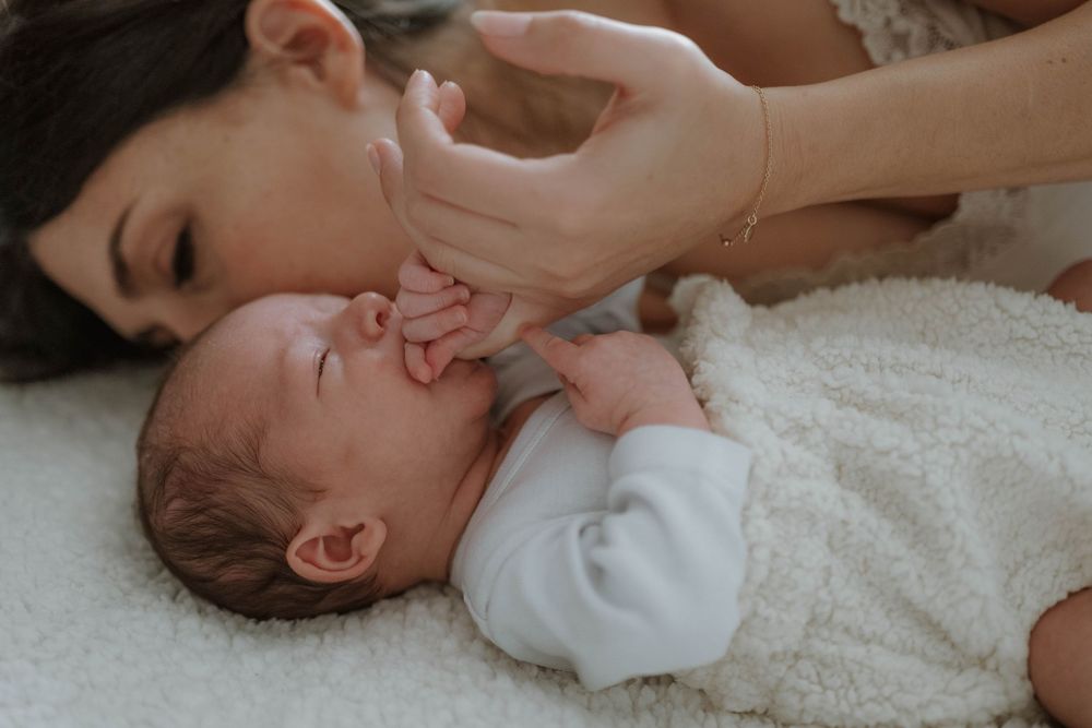 Baby receiving a gentle facial massage while lying on white bedding during a relaxing spa treatment.