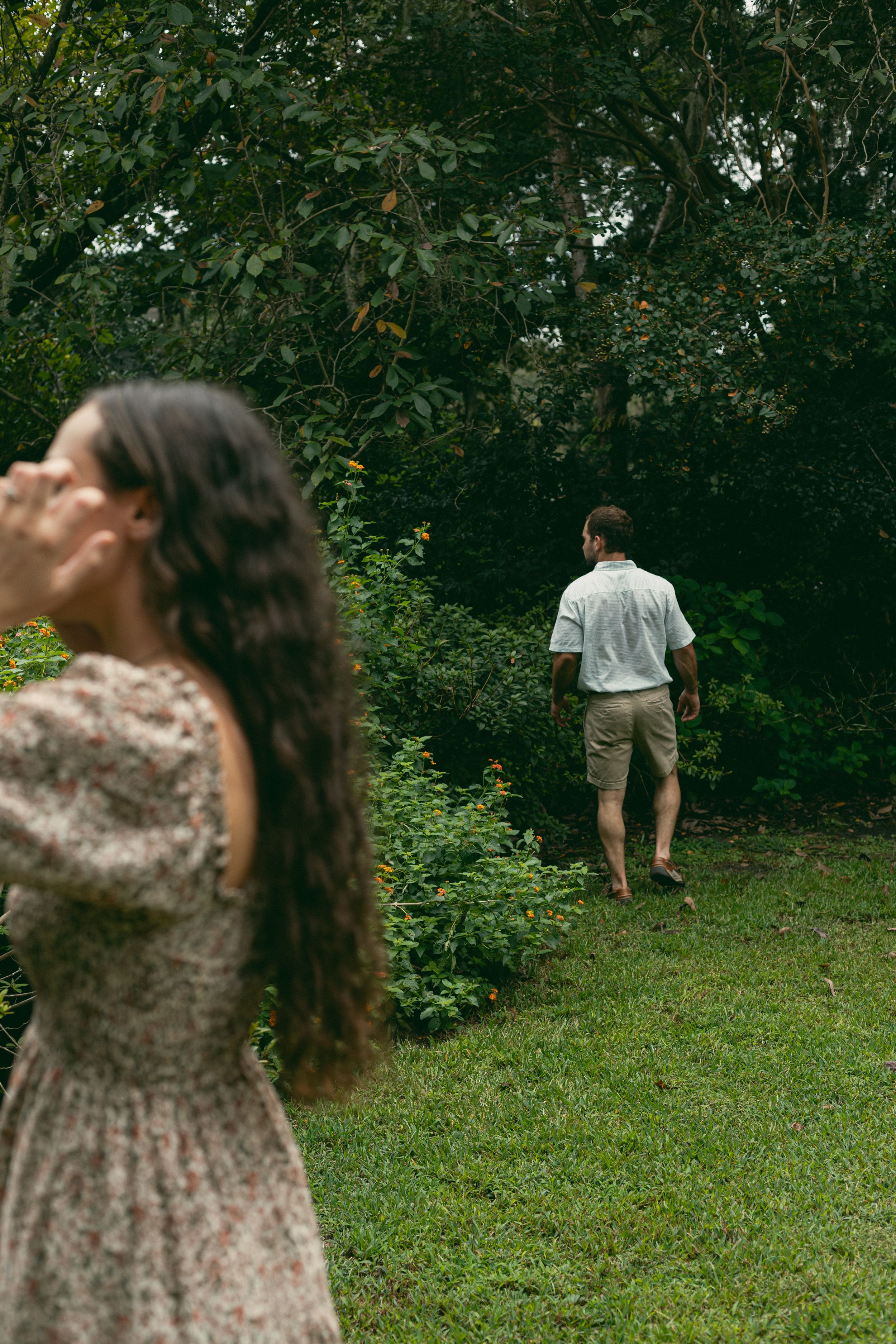 Two people in a garden setting with yellow flowers and green foliage.